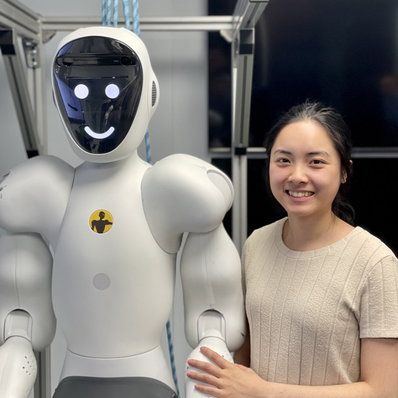 Seorang engineer berdiri di samping robot humanoid berwarna putih