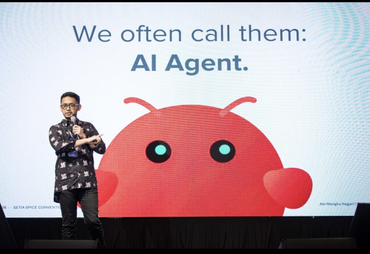 Abi Mangku presenting at PDX2026, on stage in front of the talk's AI Agent slide